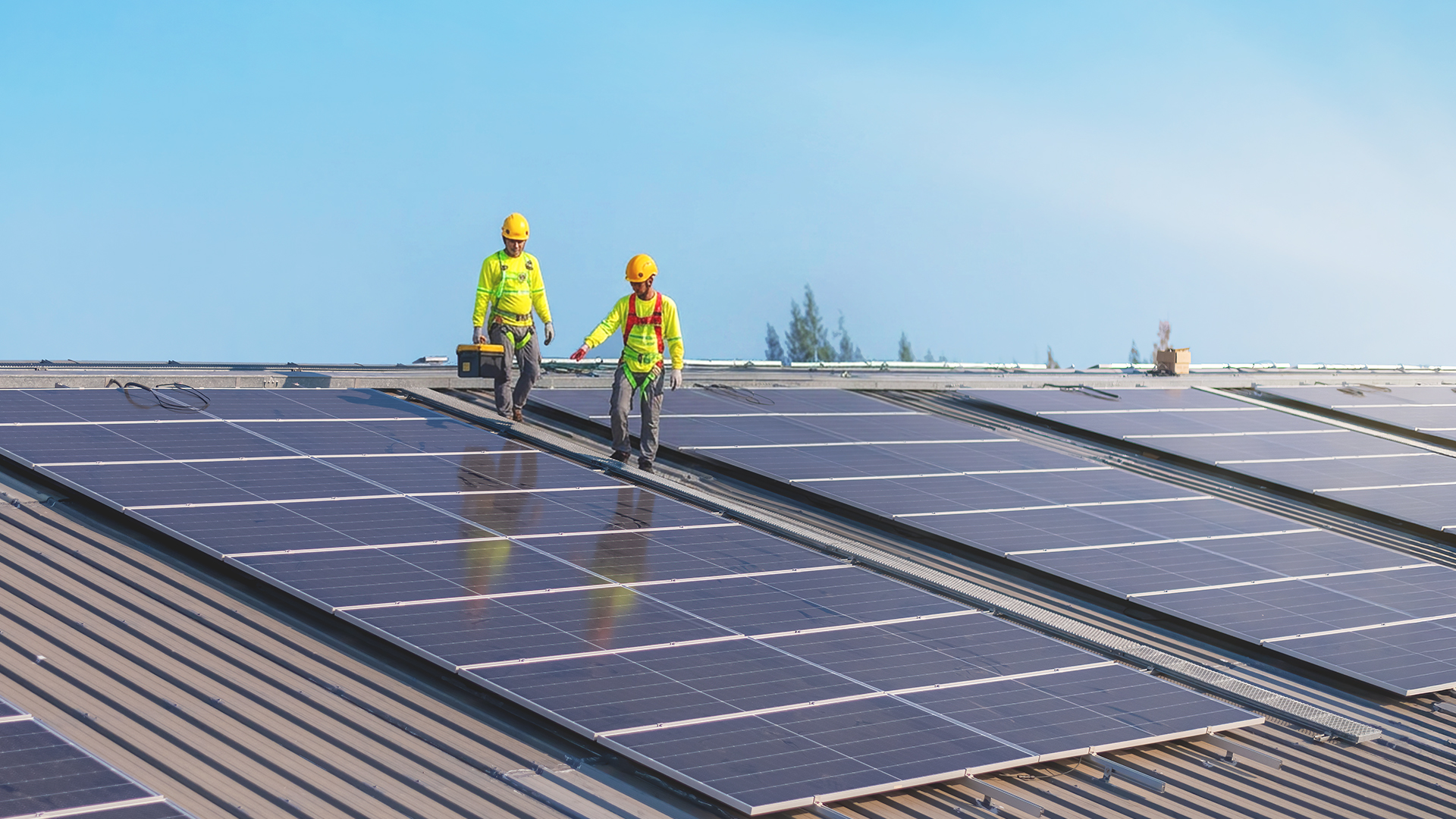 GoSolar Philippines technicians in safety gear walking across a large commercial rooftop solar panel array