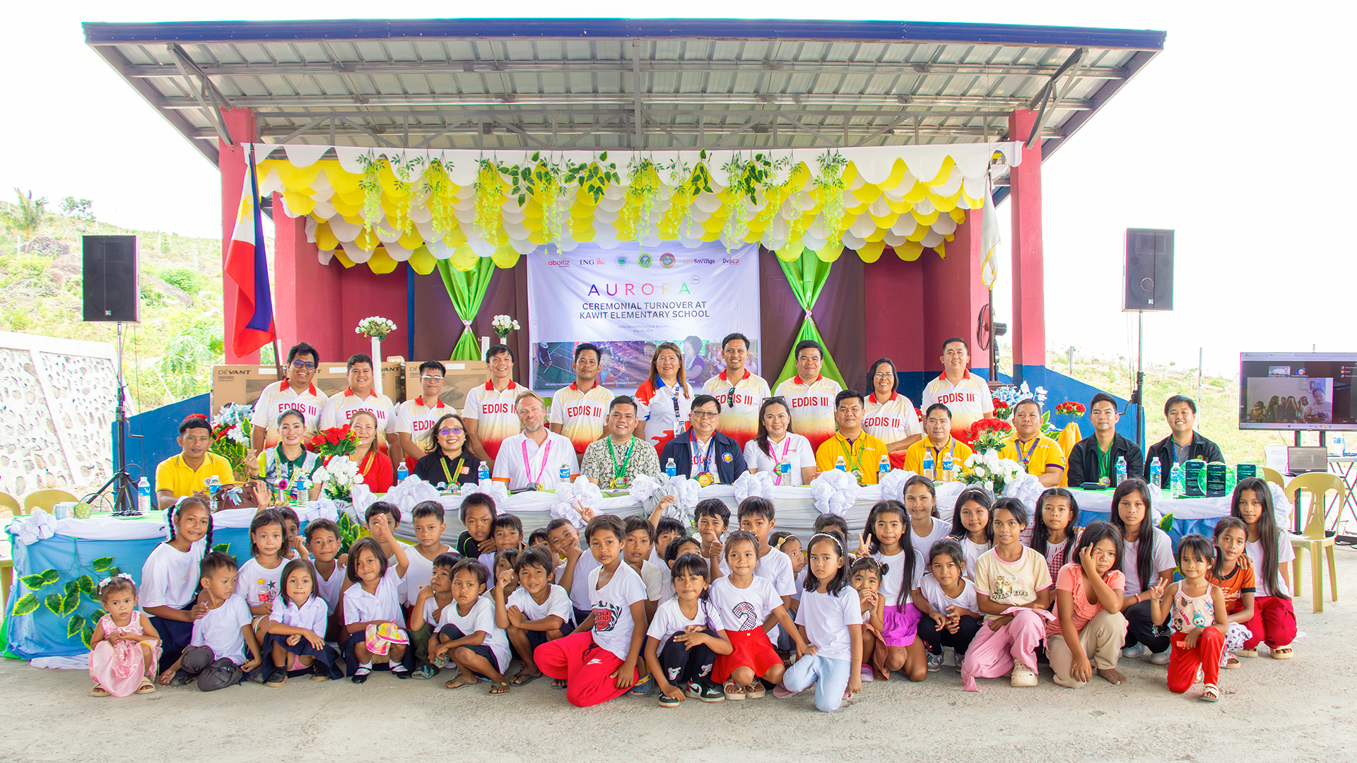 Students, teachers and partners gathered in front of a decorated stage at a last-mile school in Bulacan